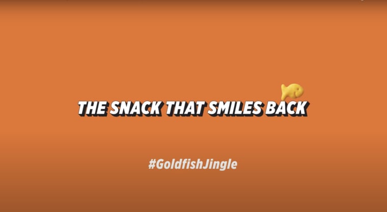 Orange background with white text that says "The Snack that smiles back" with #GoldfishJingle below