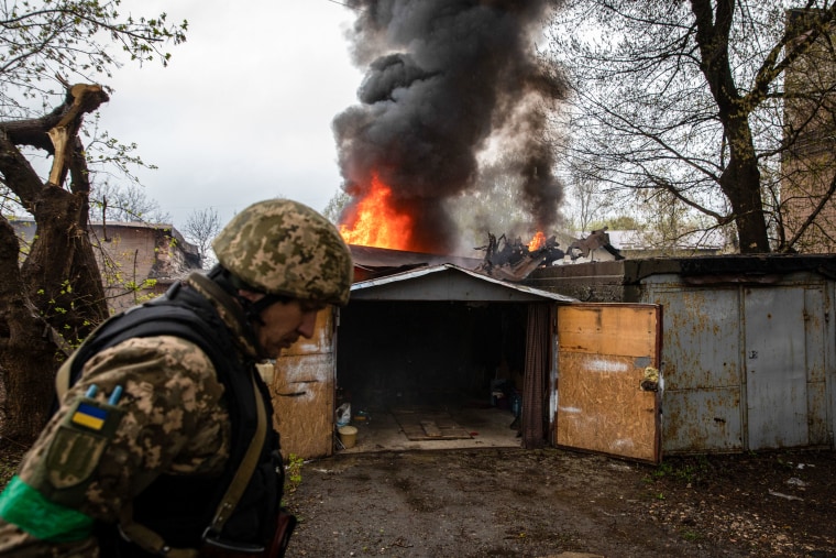 Un soldado ucraniano camina frente a un garaje en llamas tras un ataque de artillería ruso en Kharkiv, Ucrania, el 18 de abril de 2022.