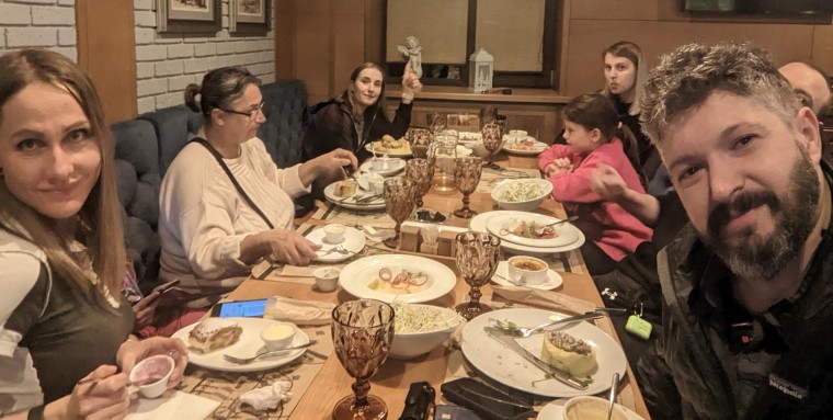 A picture of evacuees and Project Dynamo team members, enjoying a hot meal after safely being evacuated out of Russian-occupied towns in Ukraine.