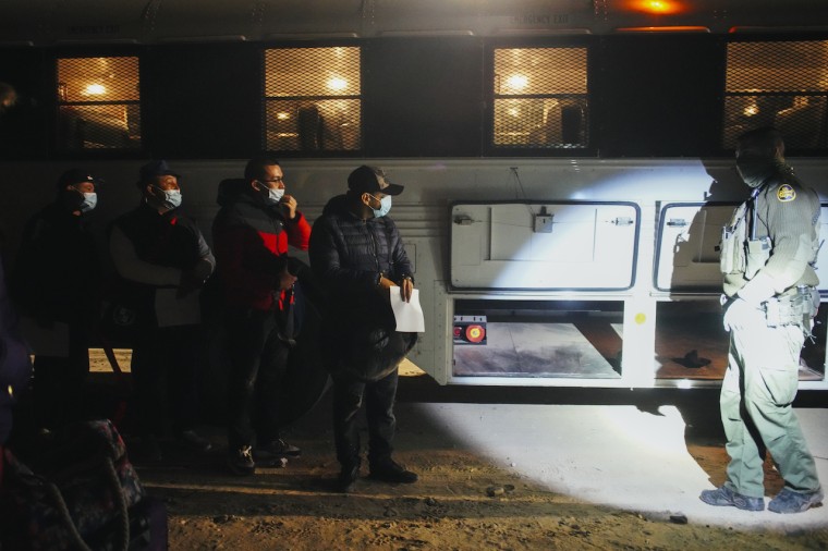 Un grupo de inmigrantes de Centroamérica, Colombia y Cuba que buscan asilo, se preparan para abordar un bus de ICE en Yuma, Arizona, que los llevará a un centro de inmigración, el 22 de febrero del 2022.