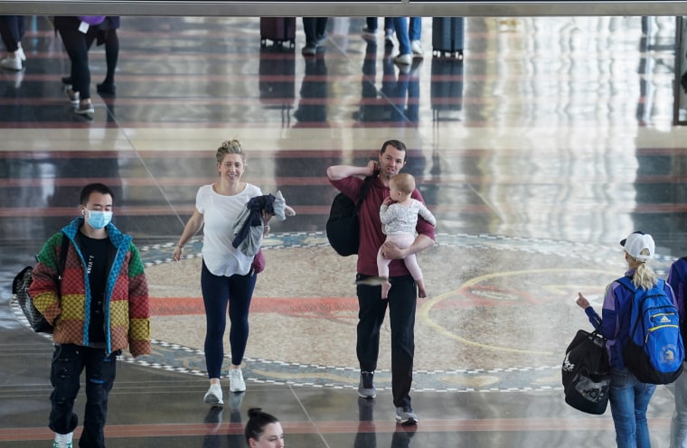 Una pareja sin mascarilla y su hijo atraviesan el Aeropuerto Nacional Ronald Reagan de Washington.
