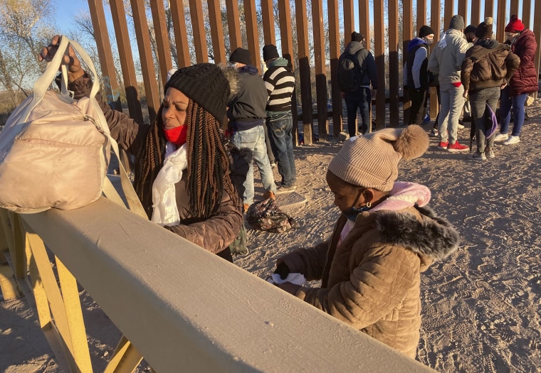 Una mujer cubana y su hija hacen fila para ser escoltadas a una camioneta de la Patrulla Fronteriza para ser procesadas en Yuma, Arizona, el 6 de febrero de 2022, con la esperanza de permanecer en Estados Unidos para solicitar asilo.