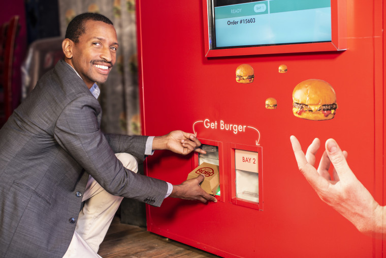 RoboBurger co-founder and CEO Audley Wilson retrieving a burger from the vending machine.