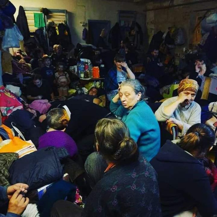 A photo of the town's citizens, held captive in the town's school's basement for weeks. There was barely enough room to stand, let alone sit or lay down.
