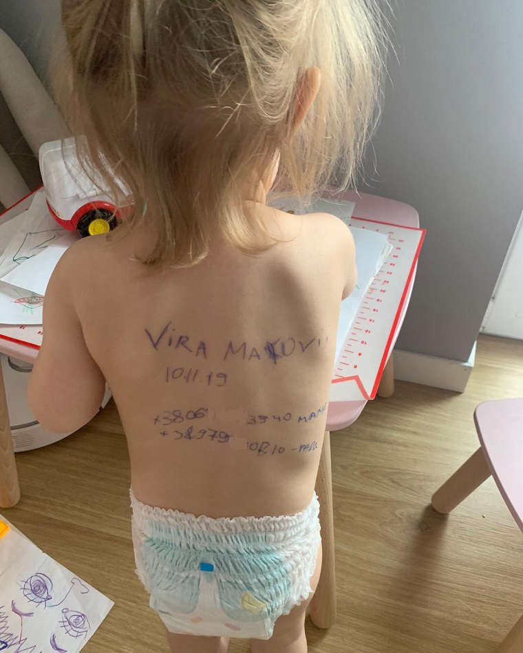 Sasha's daughter, pictured with her grandparent's contact information written on her back.