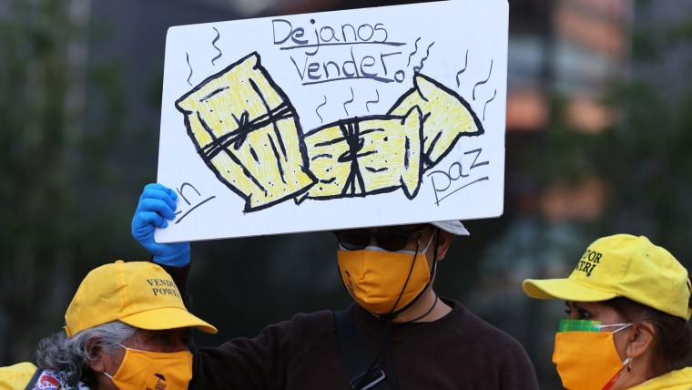 Un hombre con mascarilla sostiene una pancarta que dice "Déjanos vender" durante una protesta de vendedores ambulantes en mayo de 2021, Nueva York