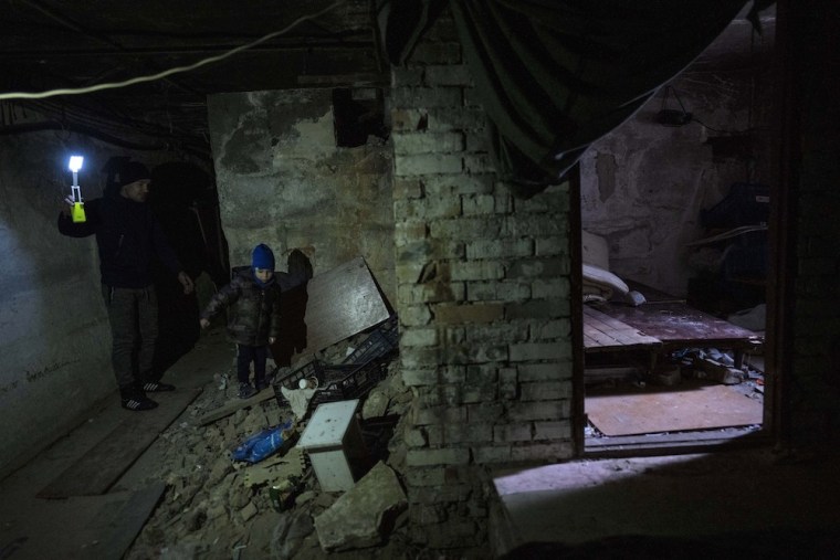 Vlad, 6, walks with his father Ivan, 40, inside the basement where they lived during the war in Bucha, in the outskirts of Kyiv, Ukraine.