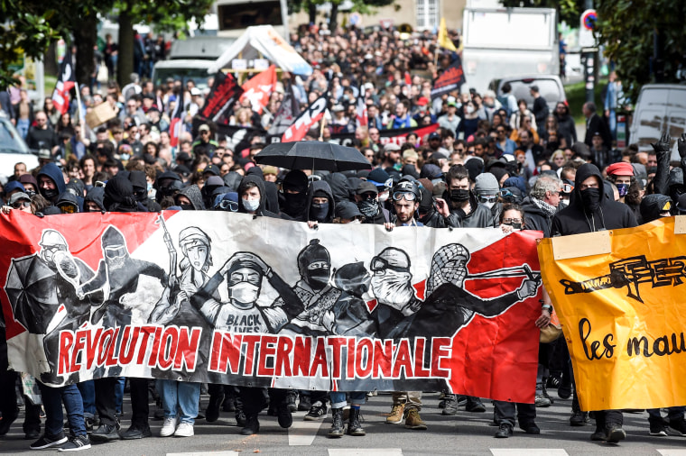 Protestors hold a banner reading "International revolution" as they take part in a May Day rally in Nantes, western France, on May 1, 2022.