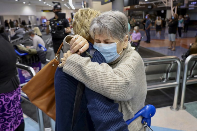 Families embrace after a flight from Los Angeles arrived at Auckland International Airport as New Zealand's border opened for visa-waiver countries on Monday.