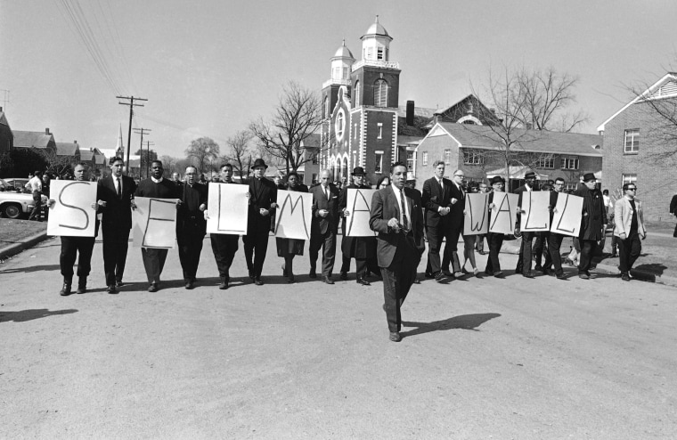 Demonstrators carrying placards that spell out “Selma Wall” march in a line from Browns Chapel in Selma, Ala., on March 14, 1965. 