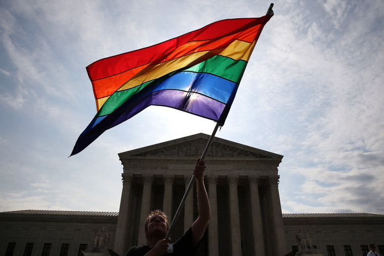 Image:  A supporter of gay marriage waves a flag in front of the Supreme Court Building June 25, 2015.