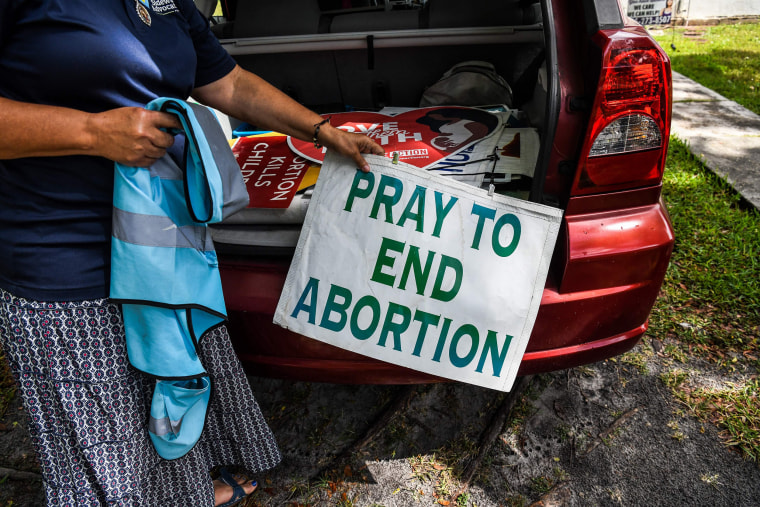 Image: An anti-abortion activist takes banners and posters from her car outside her house in Miami,  May 3, 2022.