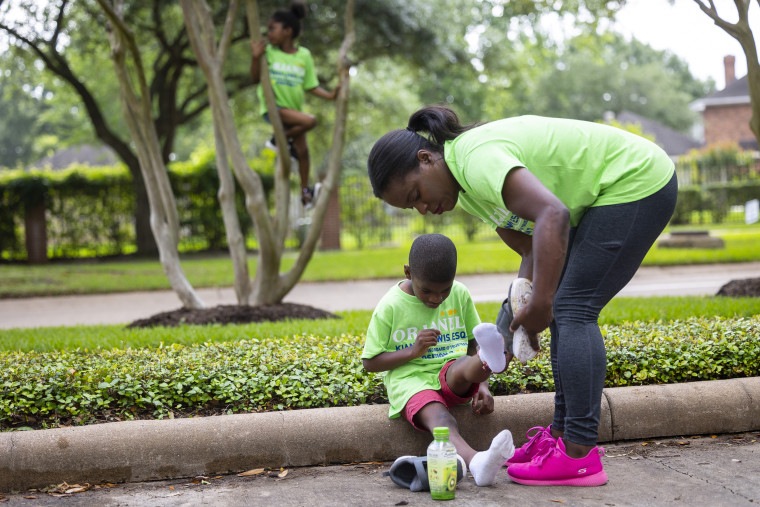 School board trustee hopeful Orjanel Lewis helps her five-year-old son Marcus with his shoes outside of the Commonwealth Clubhouse while campaigned for votes on Election Day on May 7, 2022, in Ft. Bend County, Texas.