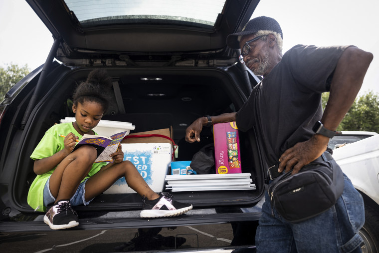 Seven-year-old Olivia Lewis completes crossword puzzles in the back of her mother’s car while her grandfather, Odell Pointer, looks on. Lewis is the daughter of school board trustee hopeful Orjanel Lewis and campaigned with her mother the entire Election Day on May 7, 2022, in Ft. Bend County, Texas.