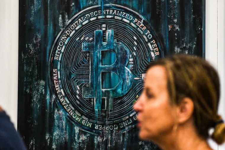 A woman walks past a Bitcoin themed art installation