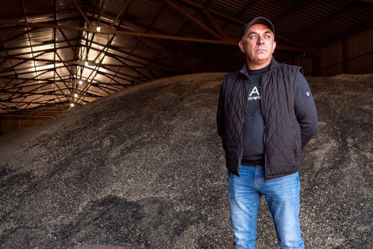 El sembrador de girasoles Roman Tarasevich se encuentra junto a una montaña de semillas de girasol sin vender en un almacén de Zaporizhzhia.