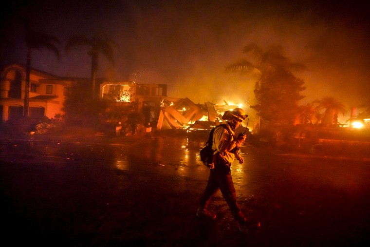 Image: A firefighter works to put out a structure burning during a wildfire on May 11, 2022, in Laguna Niguel, Calif.