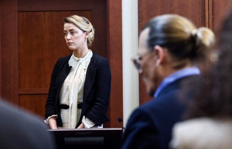 Amber Heard testifies as Johnny Depp looks on during a defamation trial at the Fairfax County Circuit Courthouse in Fairfax, Va., on May 5, 2022.
