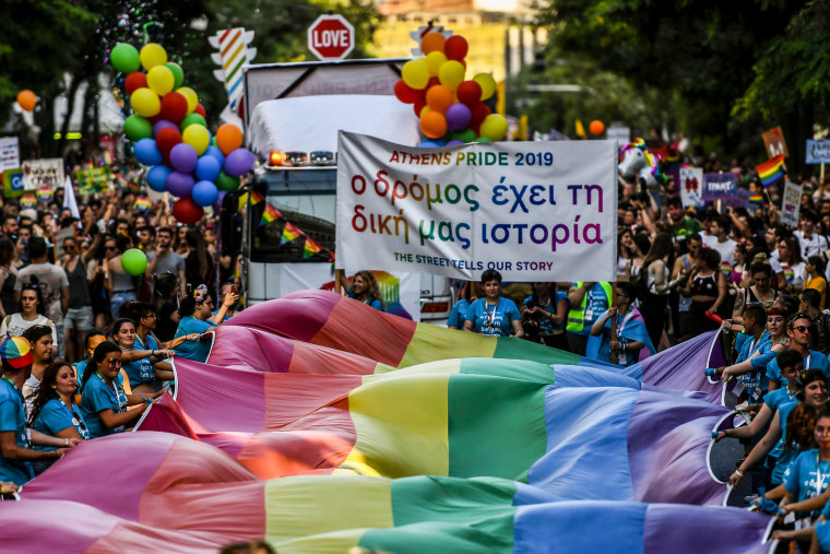 People march with a large rainbow flag as they take part in the Athens Gay Pride Parade in Athens, Greece, on June 8, 2019.