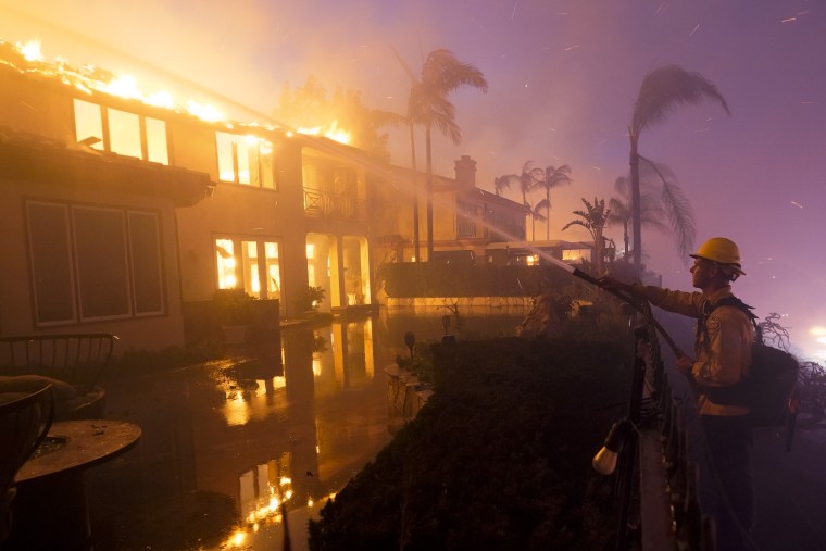 A firefighter works to put out a structure burning during a wildfire Wednesday, May 11, 2022, in Laguna Niguel, California.