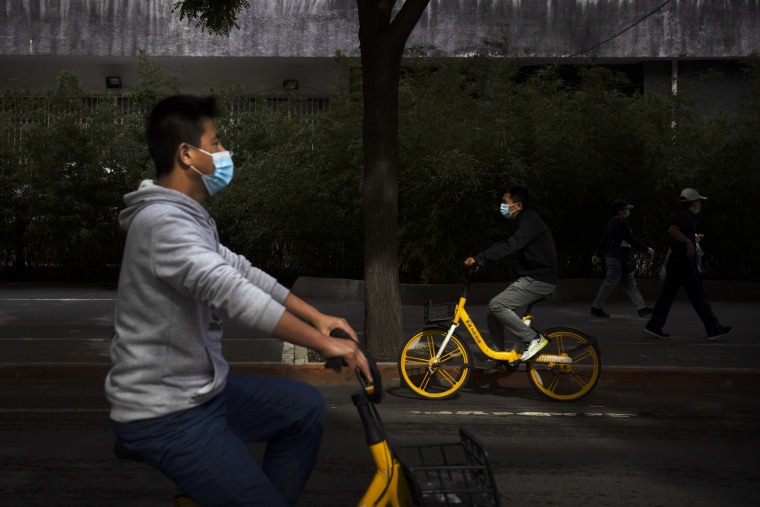 People wearing face masks walk down one of the streets of Beijing on Wednesday. 