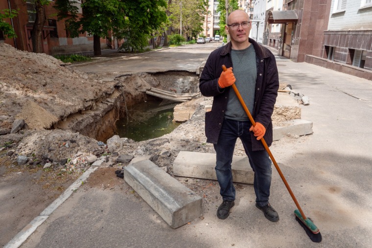 Gennady Moroz sweeps outside his apartment in Kharkiv.