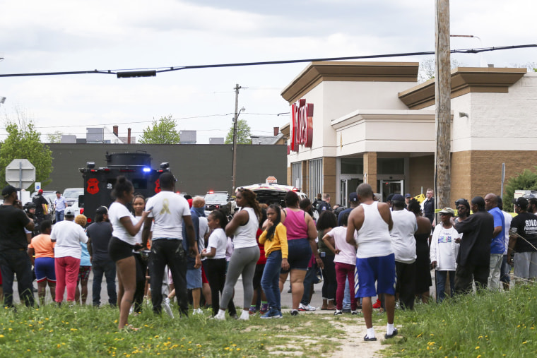 A crowd gathers as police investigate after a shooting at Tops Market