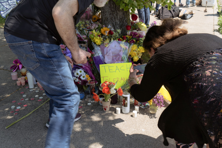 People visit a memorial on Sunday across the street from the Tops supermarket where a shooter killed 10 people and injured 3 others in Buffalo, N.Y.