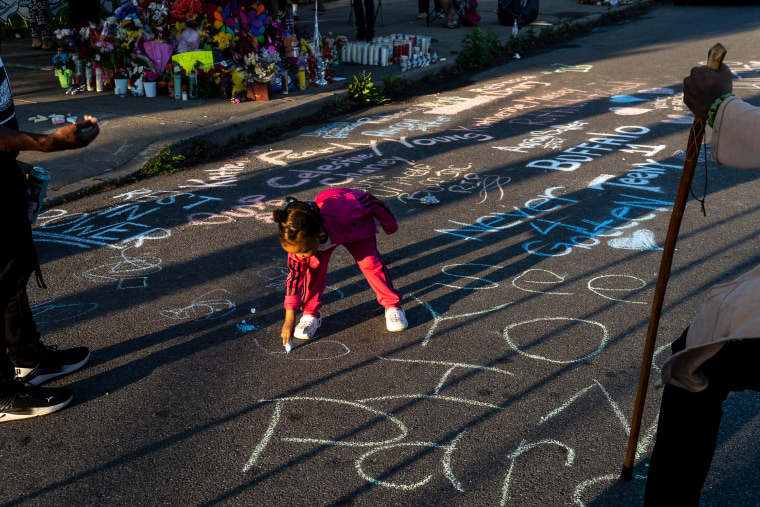 Adiyah Kijani, 2, adds a message to the memorial along the help of her father, right, Zahir Kijani, and his friend, Anthony Pierce, left, in Buffalo, N.Y. on May 15, 2022.