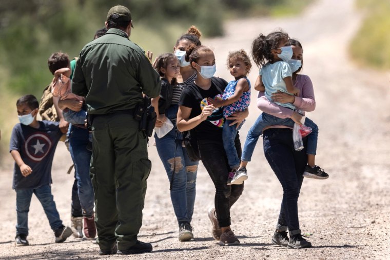 Un agente de la Patrulla Fronteriza de EE.UU. instruye a las familias inmigrantes mientras se preparan para abordar el transporte a un centro de procesamiento después de cruzar la frontera con México, en La Joya, Texas, el 13 de agosto de 2021.