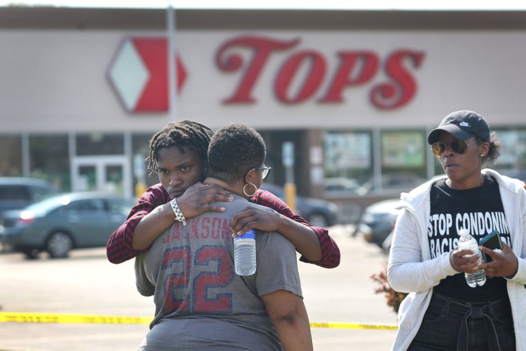 People embrace outside of the scene of a shooting at Tops Friendly Market