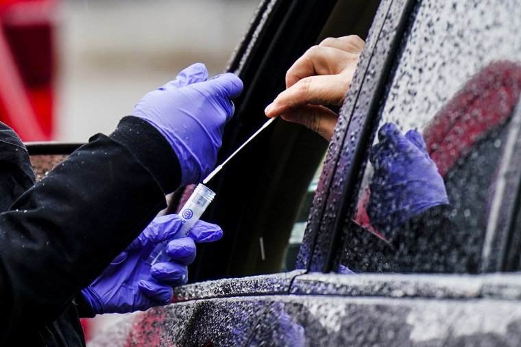 A driver places a swab into a vial at a free drive-thru Covid-19 testing site in the parking lot of the Mercy Fitzgerald Hospital in Darby, Pa., on Jan. 20, 2022.