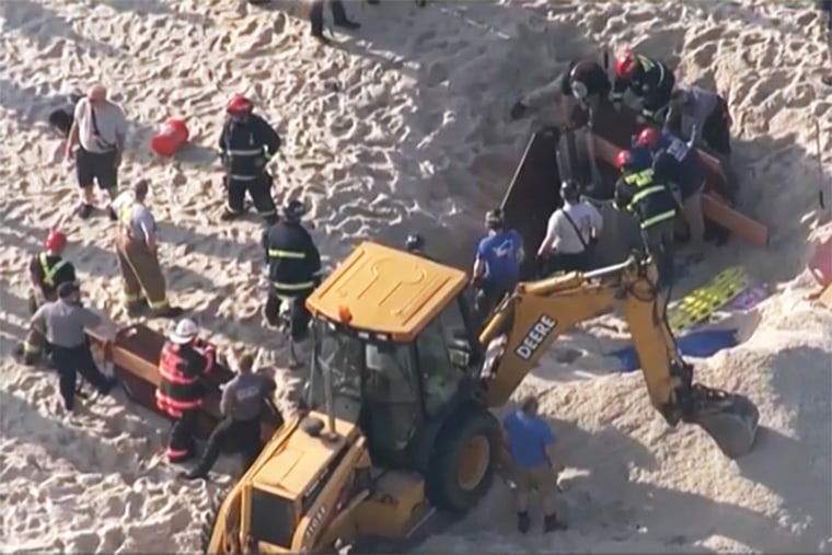 Rescue crews try to free two teenagers from a 10-foot hole in the beach that collapsed on them Tuesday in Toms River, N.J.