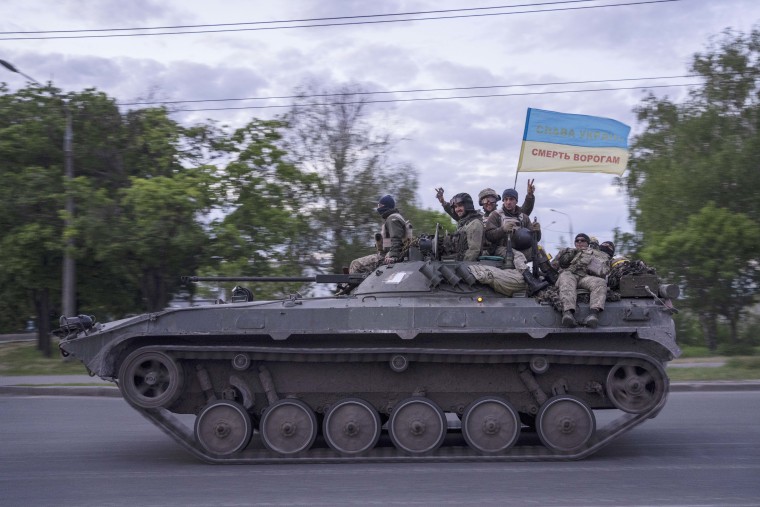 Ukrainian serviceman wave a flag which reads "Glory to Ukraine" in the Kharkiv region on May 16, 2022.