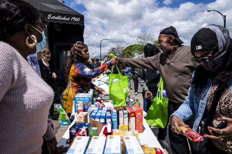 Eddie Colbert, 71, second from right, and others pick up food and supplies from a food distribution event put on by Buffalo Community Fridge along Ferry street, just blocks away from Tops Friendly Market, in Buffalo, N.Y., on May 17, 2022.