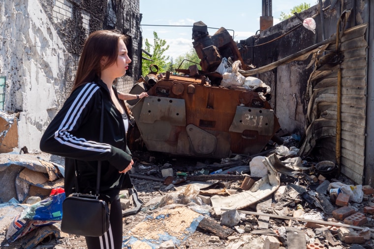 Christina Suslova stands outside a house in the village of Malaya Rohan, near Kharkiv, where Russian forces had parked an armored vehicle in a driveway.