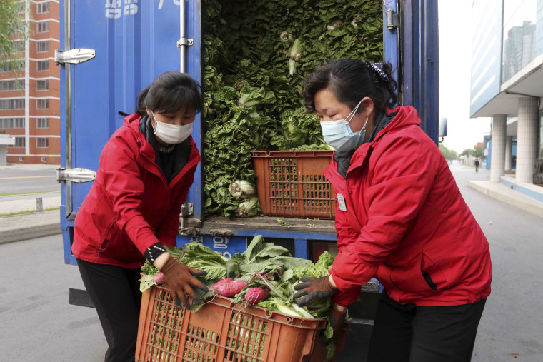 Greengrocers carry produce to supply to residents staying home as the state increased measures to stop the spread of illness in Pyongyang on Monday.