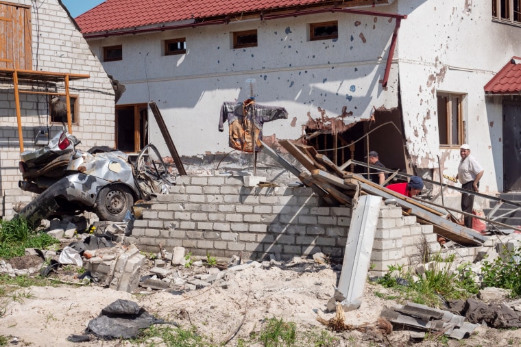 Sergey Ous, à droite, se tient devant sa maison fortement endommagée dans le village de Malaya Rohan, près de Kharkiv.