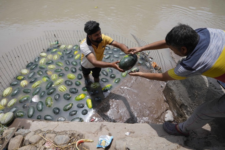 A man sells watermelons from a canal on a hot summer afternoon in Jammu, India, on Thursday. 