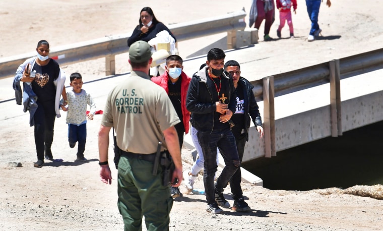 A U.S. Border Patrol officer directs migrants arriving at the border