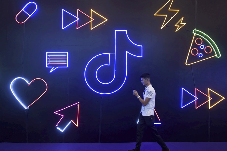 A man holding a phone walks past the TikTok, logo at the International Artificial Products Expo in Hangzhou, China on Oct. 18, 2019.