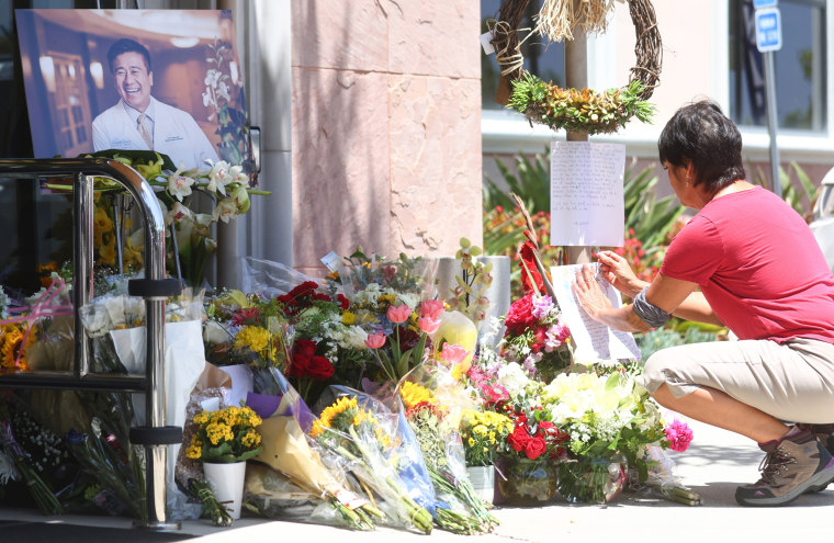 A person attaches a note at a memorial for Dr. John Cheng