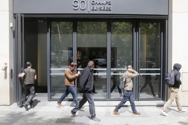Image: Four police officers, from the right, leave the building hosting McKinsey & Company France, on May 24, 2022 in Paris.
