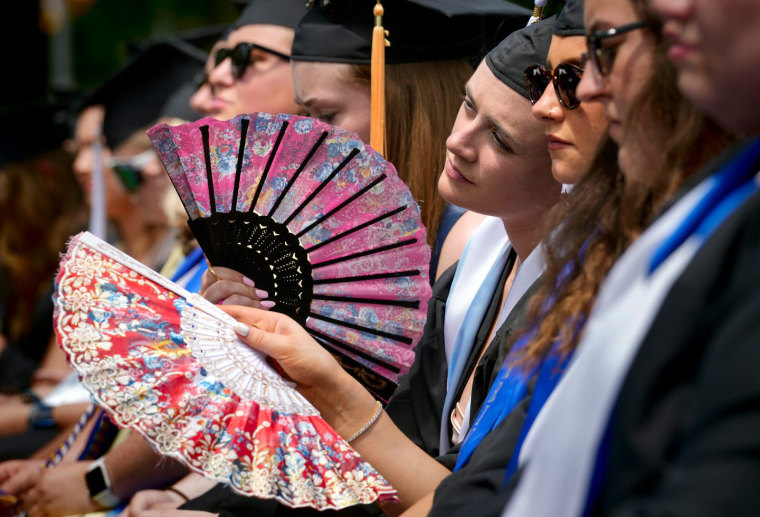 University of Rhode Island  graduates use fans to beat the afternoon heat during commencement ceremonies Sunday in Kingston, R.I.