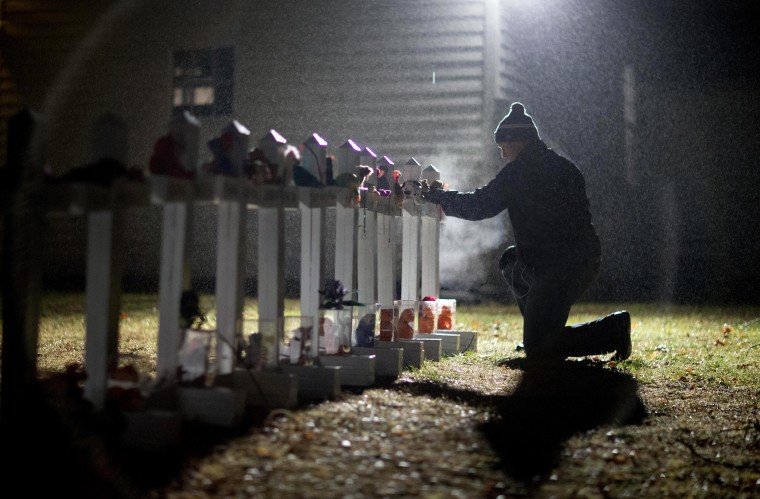 Frank Kulick adjusts a display of wooden crosses and a Jewish Star of David, representing the victims of the Sandy Hook Elementary School shooting, on his front lawn on Dec. 17, 2012, in Newtown, Connecticut.
