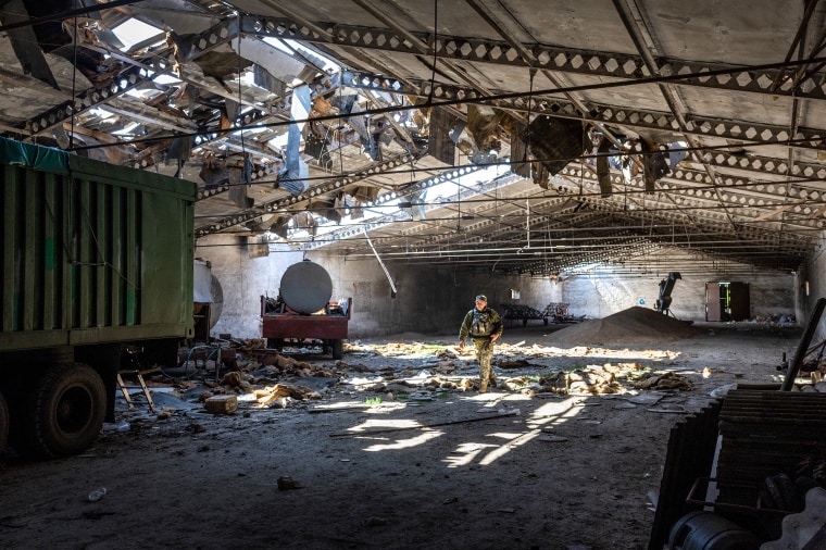 A Ukrainian army officer inspects a grain warehouse on May 6, 2022, that was shelled by Russian forces near the frontlines of Kherson Oblast in Novovorontsovka.