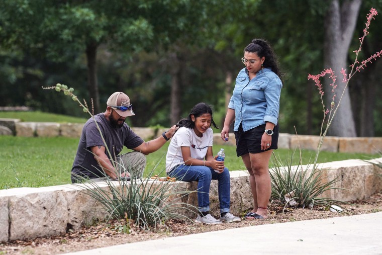 Image: Une fille pleure, réconfortée par deux adultes, devant le Willie de Leon Civic Center où des conseils en cas de deuil seront proposés à Uvalde, Texas, le 24 mai 2022.