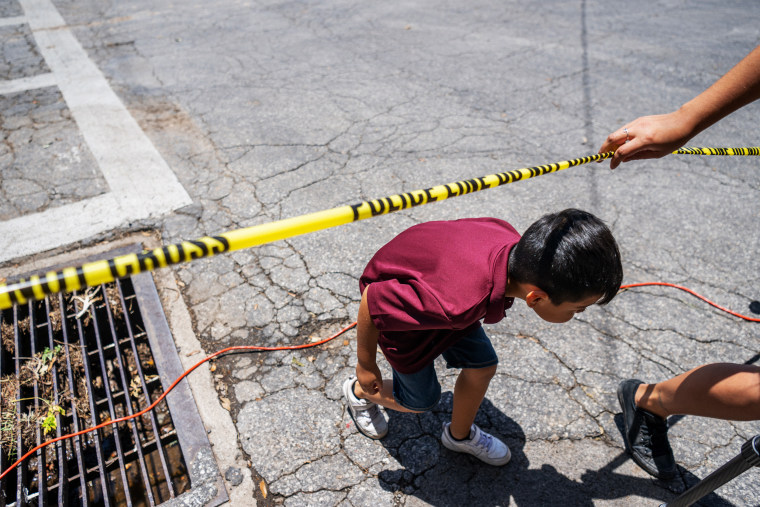 Image: A child crosses under police tape at the Robb Elementary School in Ulvade, Texas, on Wednesday. Nineteen students and two teachers were killed by a shooter on Tuesday.