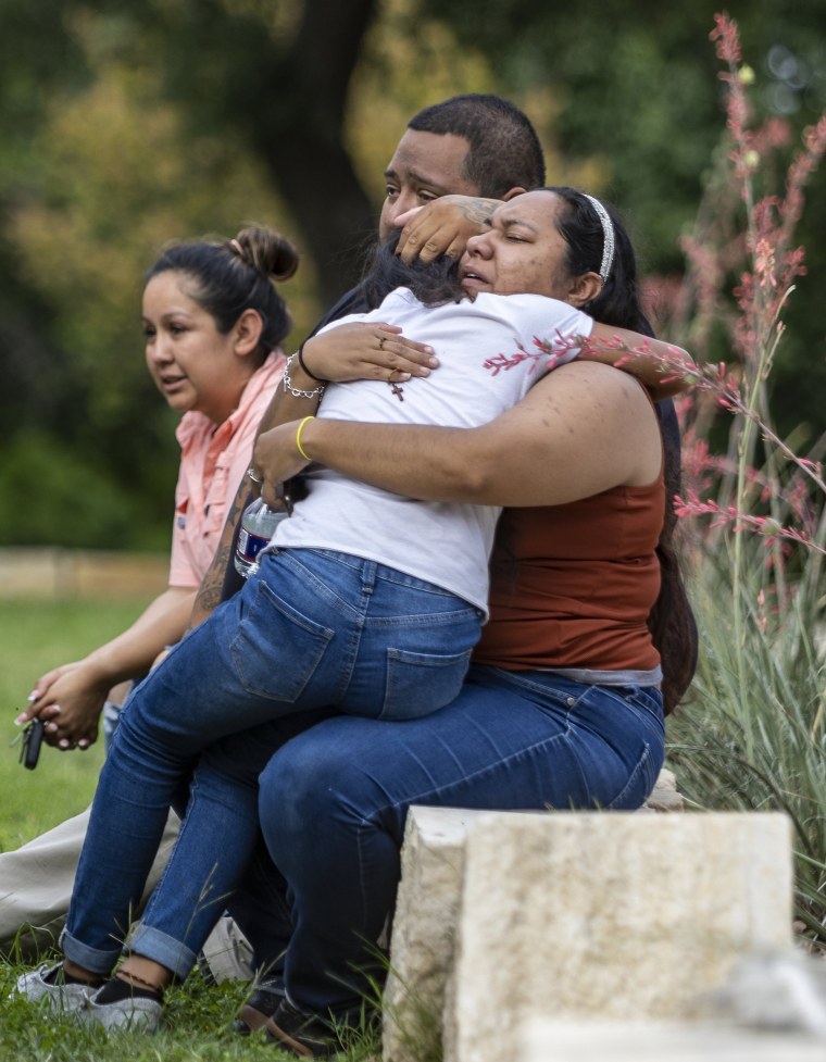 Image:  A woman clutches a child and a rosary after the shooting at Robb Elementary School in Uvalde, Texas, on Tuesday.