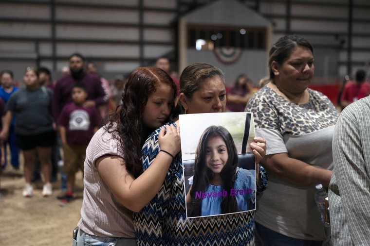Esmeralda Bravo, center, holds a photo of her granddaughter, Nevaeh, one of the Robb Elementary School shooting victims, as she is comforted by Nevaeh's cousin, Anayeli, at a prayer vigil Wednesday in Uvalde, Texas.